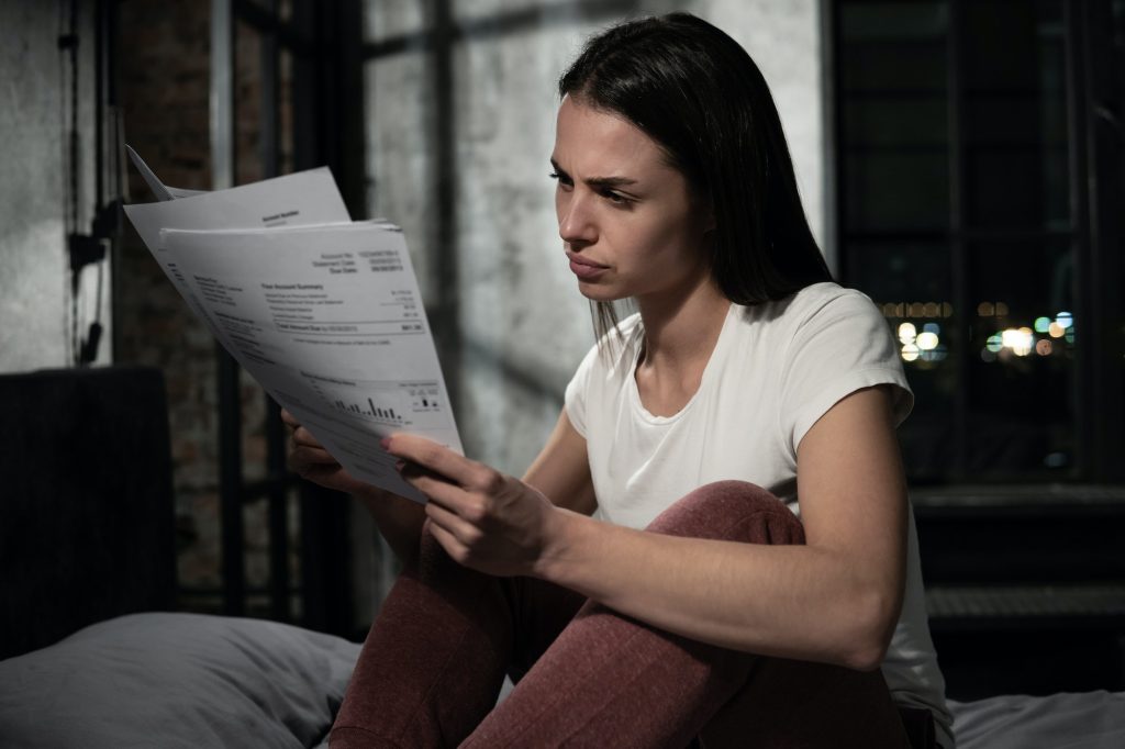 Depressed European woman deals with bills, invoices and other financial documents