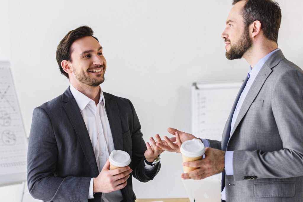 smiling handsome businessmen talking during coffee break in office